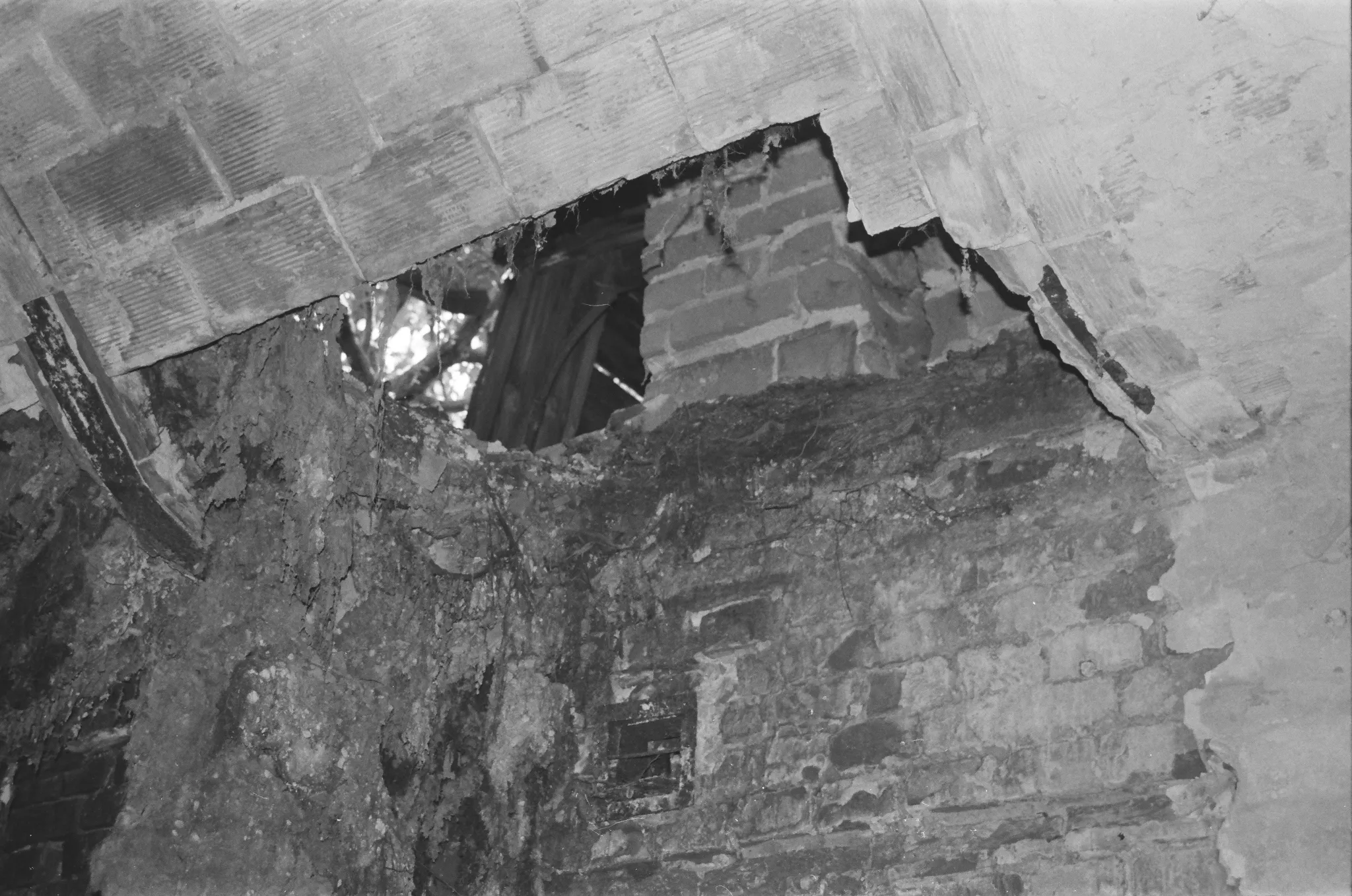 Black and white photo of a broken ceiling with visible debris and bricks.