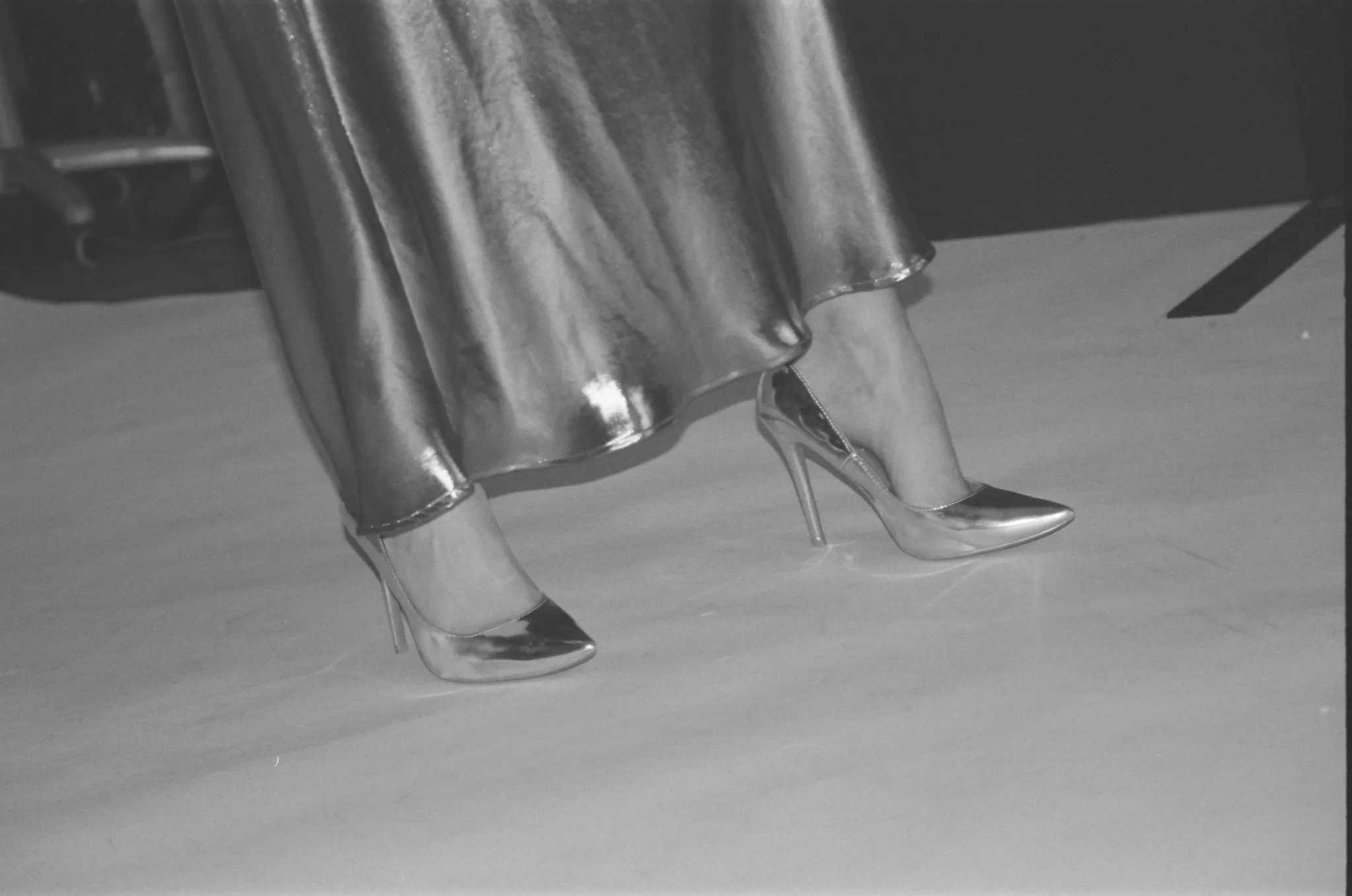 Black and white photo of metallic high heels paired with a flowing dress.