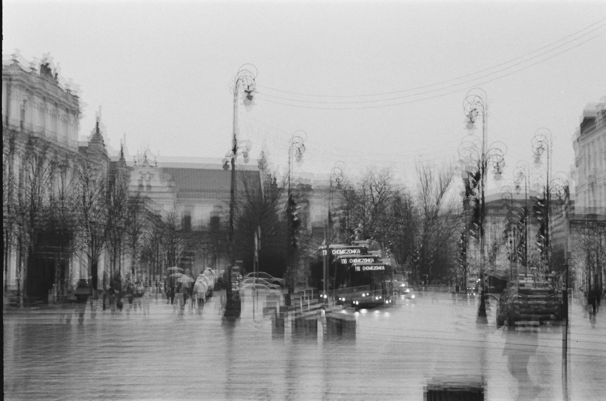 Black and white photo of a city street with blurred lights and buildings.