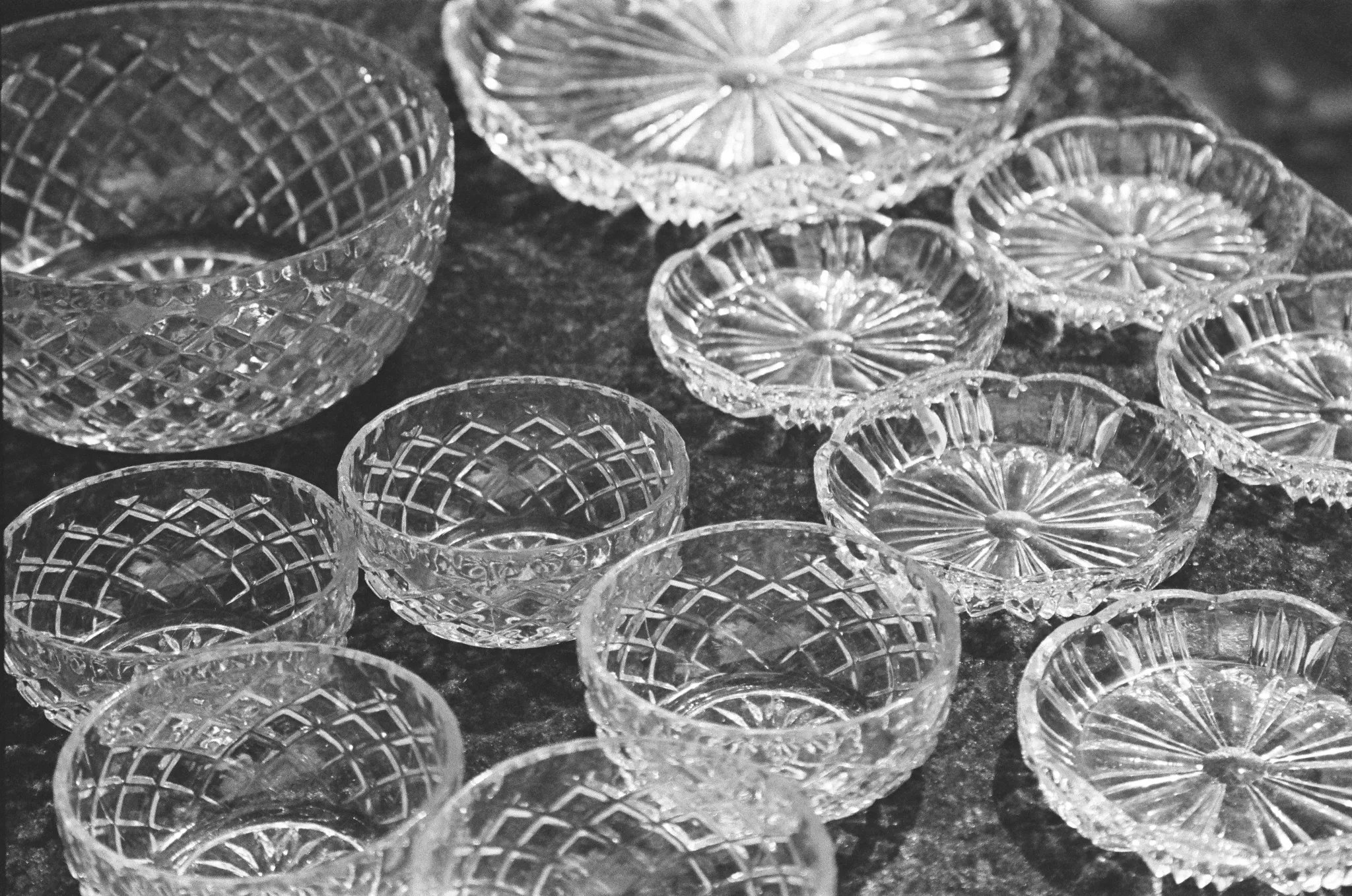Black and white photo of intricate crystal dishes on a reflective surface.